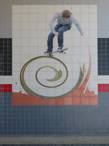 912845 Afbeelding van een tegelplateau met een afbeelding van een jonge skater op een golf, in de oostelijke muur van ...